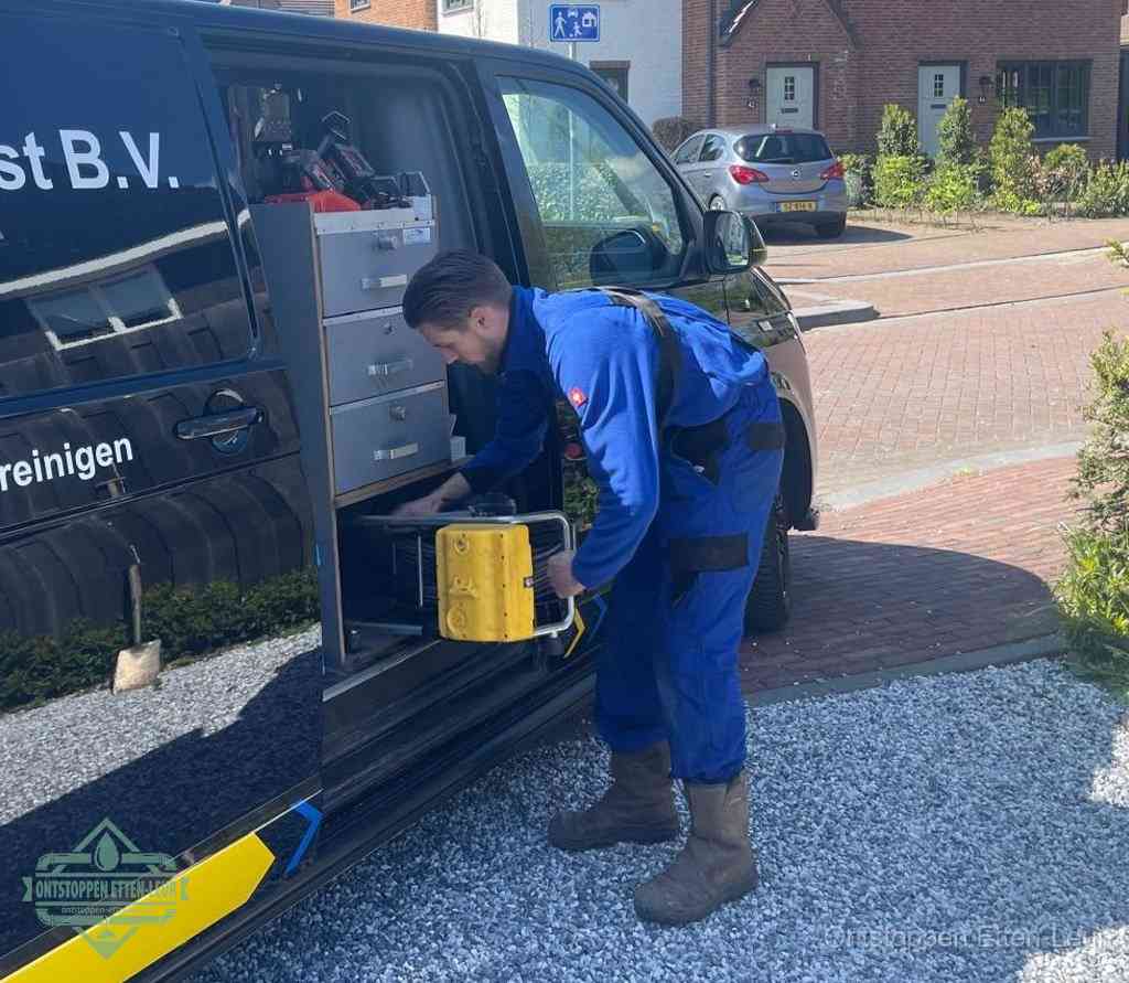 Een monteur pakt buiten op de oprit gereedschap uit de bedrijfsbus, het moment om een professional in te schakelen voor een verstopte afvoer in Etten-Leur