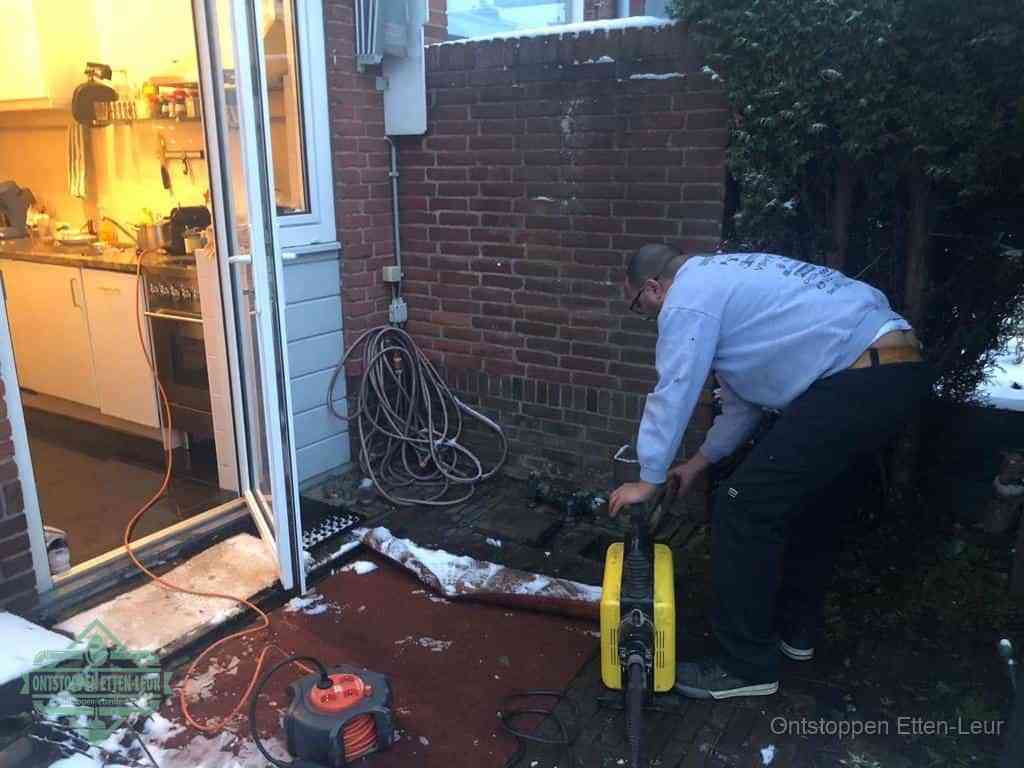 Een monteur werkt buiten bij een open riool-/grondput met een elektrische ontstoppingsmachine om een verborgen afvoerprobleem op te sporen in Etten-Leur