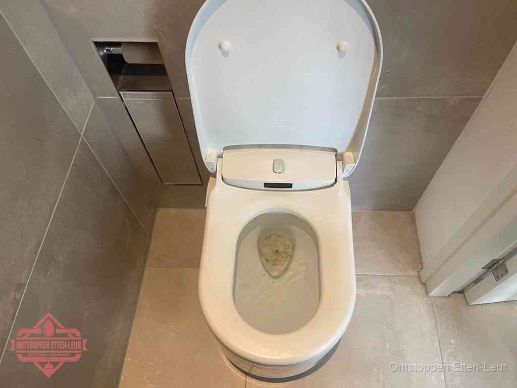 Een wit hangtoilet waarin een prop wc-papier op het water blijft drijven, een duidelijk signaal van een verstopte wc in Etten-Leur
