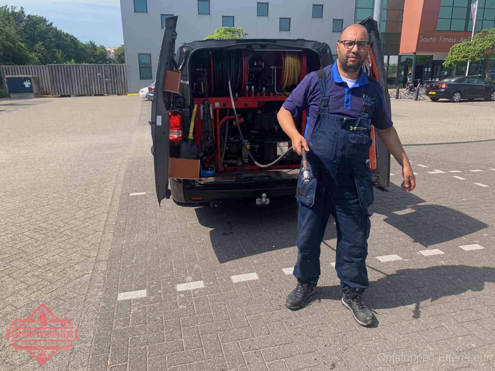 Een monteur bij zijn bestelbus met een hogedruk- en rioolreinigingsunit, klaar om de oorzaak van terugkerende wc-verstoppingen aan te pakken in Etten-Leur