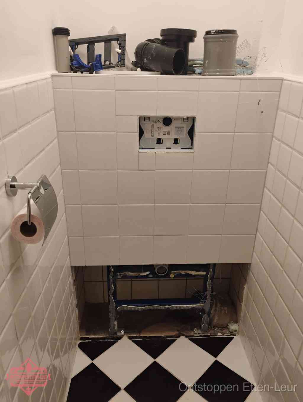 Een toiletruimte waar het hangtoilet en de inbouwreservoir-onderdelen zijn vrijgelegd voor onderhoud, periodiek nazicht voorkomt een wc-verstopping in Etten-Leur