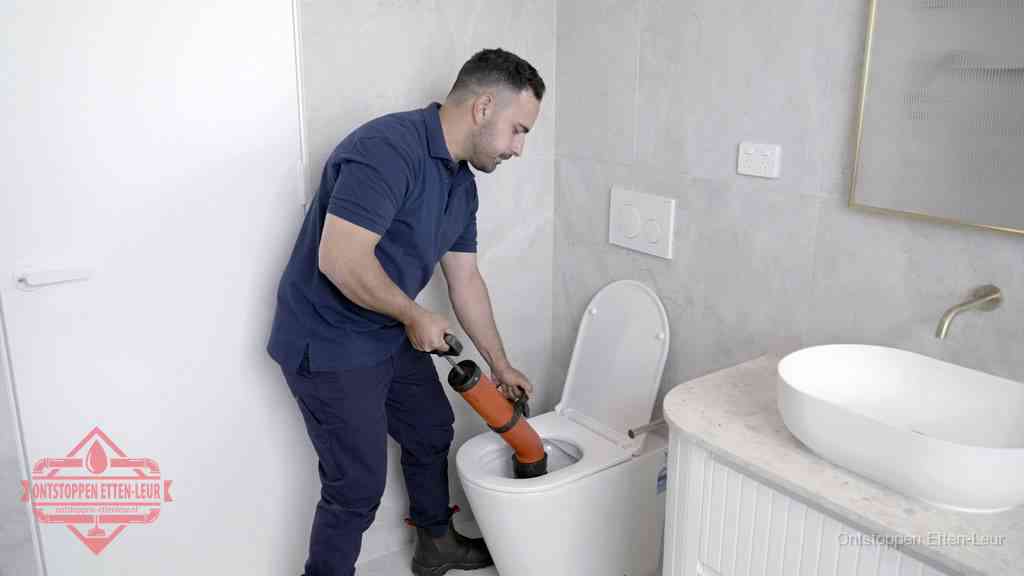 Een monteur gebruikt een handmatige perspomp (toiletontstopper) op een wandcloset tijdens het professioneel wc ontstoppen in Etten-Leur